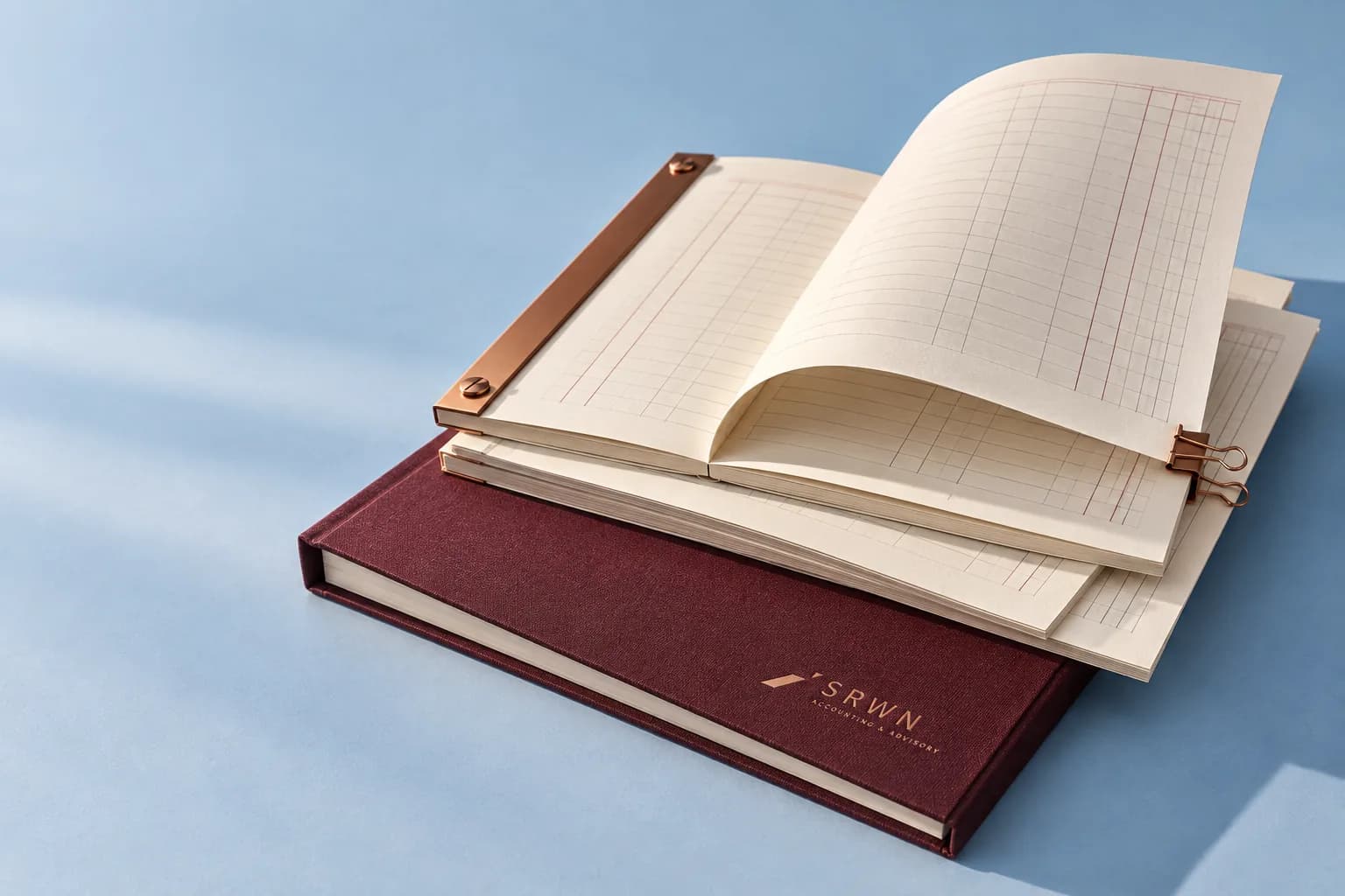 SRWN report folios and ruled ledger pages with copper binding on a blue surface